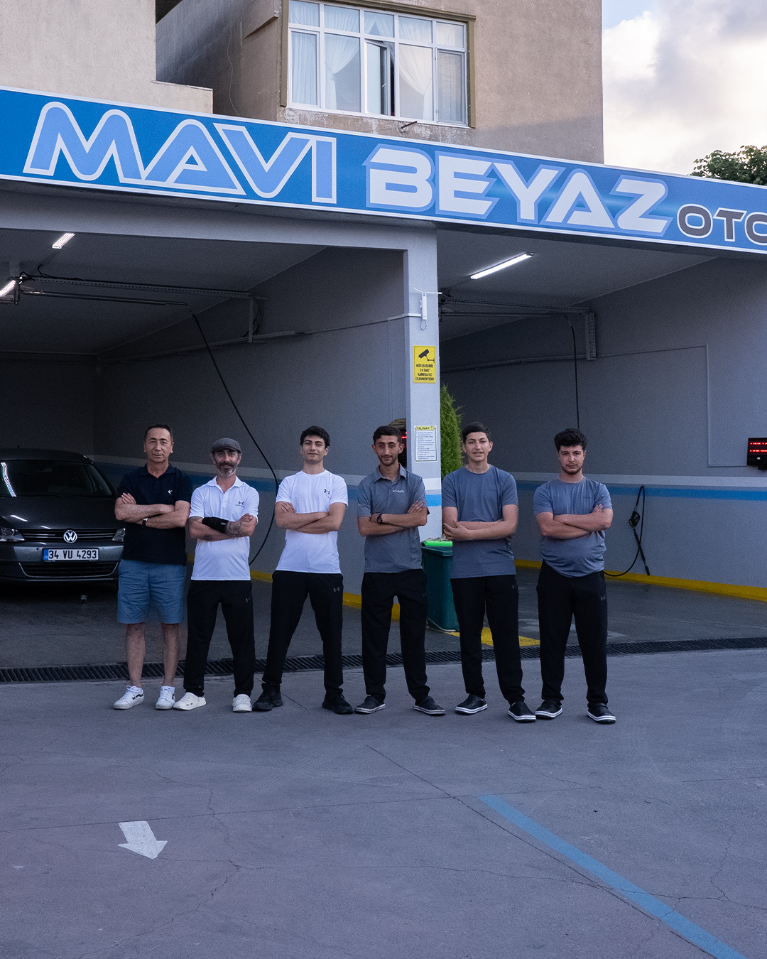 Mavi Beyaz Oto Yıkama ekibi, yıkama bölmeleri önünde
